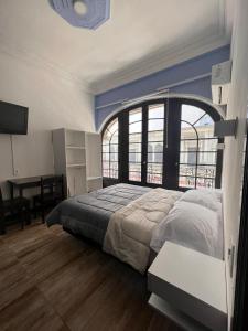 a bedroom with a bed with a large window and a desk at Nuevo Hotel Aramaya in Montevideo