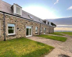 a stone house with a grass yard in front of it at Buttercup Cottage in Killean