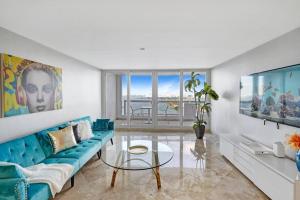 ein Wohnzimmer mit einem blauen Sofa und einem Glastisch in der Unterkunft First Class! - Crystal clear water views! in Miami