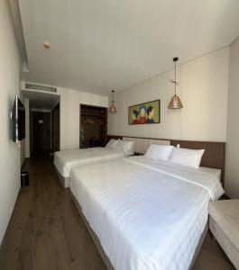 2 grote witte bedden in een hotelkamer bij Apec Chambay Mũi Né Marble Team 