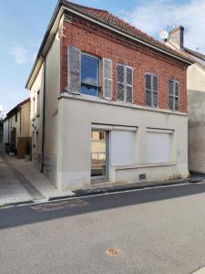 un bâtiment en briques avec deux portes de garage dans une rue dans l'établissement Les Bras de Morphée, à Avize