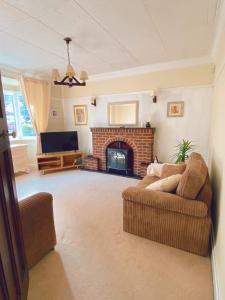 a living room with a couch and a fireplace at Large Home with 5 car Parking next to Train station, Airport, NEC in Marston Green