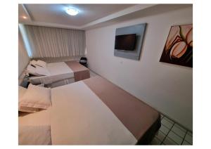 a hotel room with three beds and a flat screen tv at Garanhuns Palace Hotel in Garanhuns