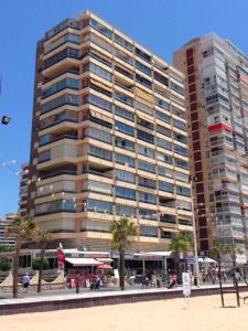 a large building with palm trees in front of it at Benidorm Carolina Beach & Pool in Benidorm