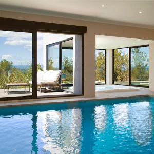 a house with a swimming pool in front of windows at Villa du Belvédère, piscine intérieure, spa et hammam in Montagnac