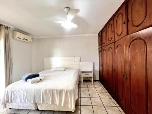 een slaapkamer met een wit bed en een houten kast bij Jurere in Meia Praia