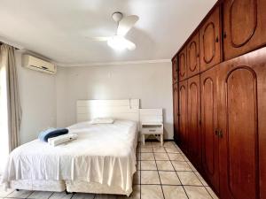 Un dormitorio con una cama blanca y un armario de madera. en Jurere, en Meia Praia