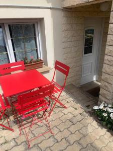 Deux chaises rouges et une table rouge devant une porte dans l'établissement Appartement Ensoleillé à 15 minutes de Paris, à Vitry-sur-Seine