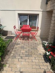a red table and chairs on a stone patio at Appartement Ensoleillé à 15 minutes de Paris in Vitry-sur-Seine