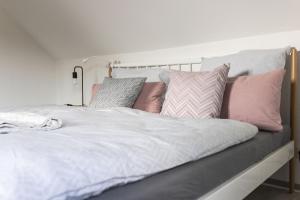 Una cama con almohadas rosas y grises. en Auszeit Altenhorst, en Schalksmühle