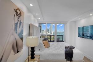 a white bedroom with a bed and a large window at Make It Happen! Brand New with Amazing Water Views in Miami