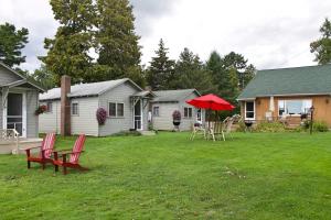 a yard with chairs and a red umbrella and a house at Pine Haven Beach Resort in Tawas City