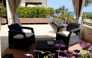 un balcón con 2 sillas, una mesa y flores en Darlex Apartments Galatex Beach Center, en Limassol