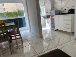 a kitchen with white cabinets and a table and a table and chairs at Apart. Bela Vista in Pôrto Ferreira