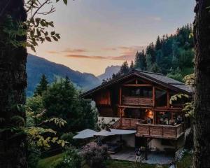 una cabaña de madera en las montañas con puesta de sol en Superbe CHALET (14 personnes) & SAUNA au pied du Mont Blanc en Les Contamines-Montjoie