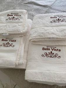 three white towels with writing on them on a table at Apart. Bela Vista in Pôrto Ferreira