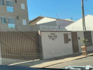 a fence with a sign on it next to a building at Apart. Bela Vista in Pôrto Ferreira