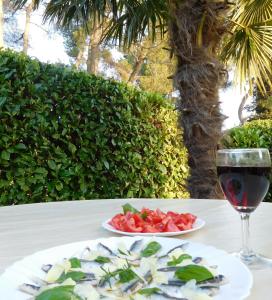 uma mesa com dois pratos de comida e um copo de vinho em Apartments Marija & Ivana, Malinska em Malinska