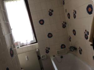 bagno con vasca, servizi igienici e finestra di Monolocale Bixio a Ponte di Legno a Ponte di Legno