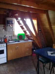 a kitchen with a sink and a stove and a table at Cabañas Las Acacias in Trevelín +11 photos