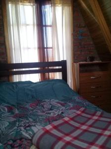 a bedroom with a bed and a dresser and windows at Cabañas Las Acacias in Trevelín