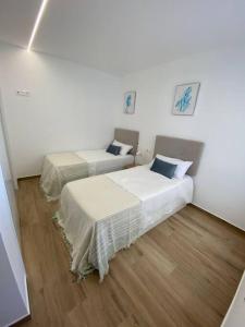 2 łóżka w pokoju z drewnianą podłogą w obiekcie Casa Amigos nieuw appartement in Velapi - Los Alcazares w mieście San Javier