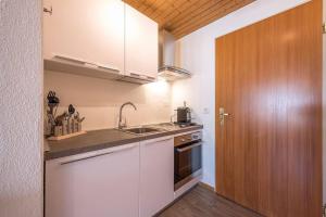 a kitchen with white cabinets and a sink and a wooden door at Studio centralissimo a St. Moritz in St. Moritz