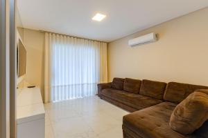 sala de estar con sofá marrón y ventana en Casa com Jacuzzi ideal para Férias de Famílias - 3 dorms 6 pessoas en Bombinhas