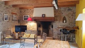 a living room with a stone fireplace with a television at Les longères du Trieux in Lézardrieux