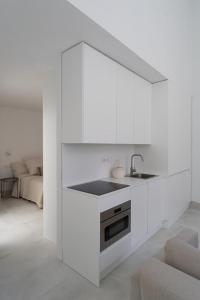 马德里Loft in the city的厨房配有白色橱柜、水槽和沙发 更多11张照片