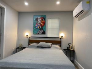 1 dormitorio con 1 cama con 2 mesitas de noche y una pintura en Betterplace 2-Bedooms Walk to Armature Works and Downtown Tampa, en Tampa