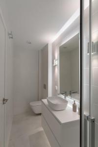 uma casa de banho branca com um lavatório e um espelho em Loft in the city em Madrid
