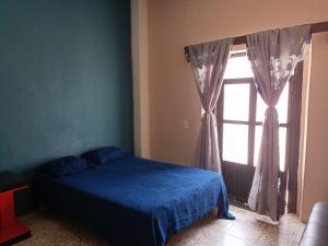 a bedroom with a blue bed and a window at Casa Flores in Zacatecas