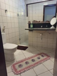 a bathroom with a toilet and a mirror and a rug at Hostel Atairú in Natal