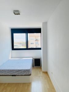 a white room with a bed and a window at Habitaciones confort in Benetúser