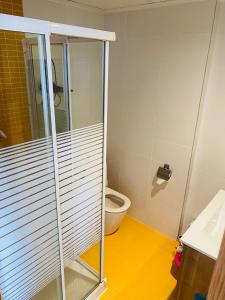 uma casa de banho com um WC e uma cabina de duche em vidro. em Habitaciones confort em Benetúser