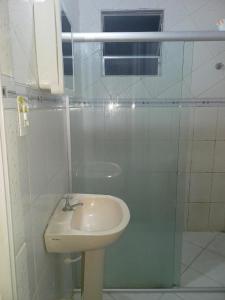 a white bathroom with a sink and a shower at Kitnet praia de Atalaia, Aracaju - Sergipe in Aracaju