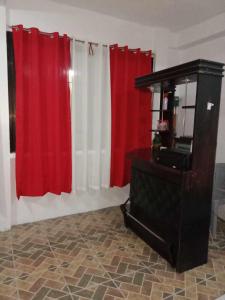- un salon avec des rideaux rouges et blancs et un bureau dans l'établissement 4jMarte Home Stay, à Imus