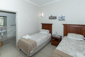 a bedroom with two beds and a bathroom with a sink at The Herolds Bay in Herolds Bay