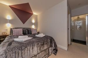 a bedroom with a large bed with two towels on it at MK CITY CENTRE, THE DIAMOND SUITE, FREE Parking Space, PREMIUM SPACIOUS Apartment with FOOSBALL TABLE in Milton Keynes