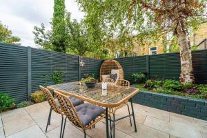 a patio with a table and chairs and a fence at Cozy 2 Bedroom garden flat in London +4 photos