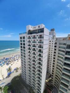 uma vista para dois edifícios altos e uma praia em Apartamento Pé na Areia na Praia das Pitangueiras no Guarujá