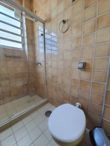 uma casa de banho com um chuveiro e um WC. em Apartamento Pé na Areia na Praia das Pitangueiras no Guarujá