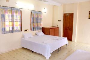 a bedroom with a white bed and a wooden door at Perfect Homestay Ujjain in Ujjain