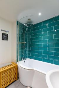 溫特爾頓海濱的住宿－Sams Snug，浴室设有浴缸,铺有蓝色瓷砖。
