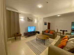 a living room with a couch and a tv at Homely 2-Bedroom at Victoria Place in Dar es Salaam