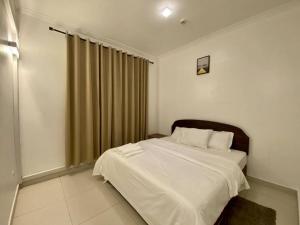 a bedroom with a bed with white sheets and a window at Homely 2-Bedroom at Victoria Place in Dar es Salaam