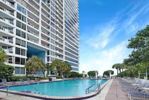 a swimming pool in front of a tall building at Cloud Nine! Direct Water Views of Bay & Ocean! in Miami