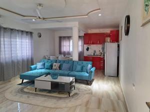 a living room with a blue couch and a kitchen at Pool House Retreat in Accra in Accra