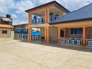 a house with a blue roof with a balcony at Pool House Retreat in Accra in Accra